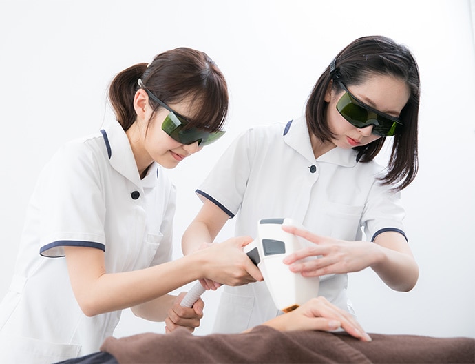 脱毛施術の練習をする新人看護師と先輩スタッフ